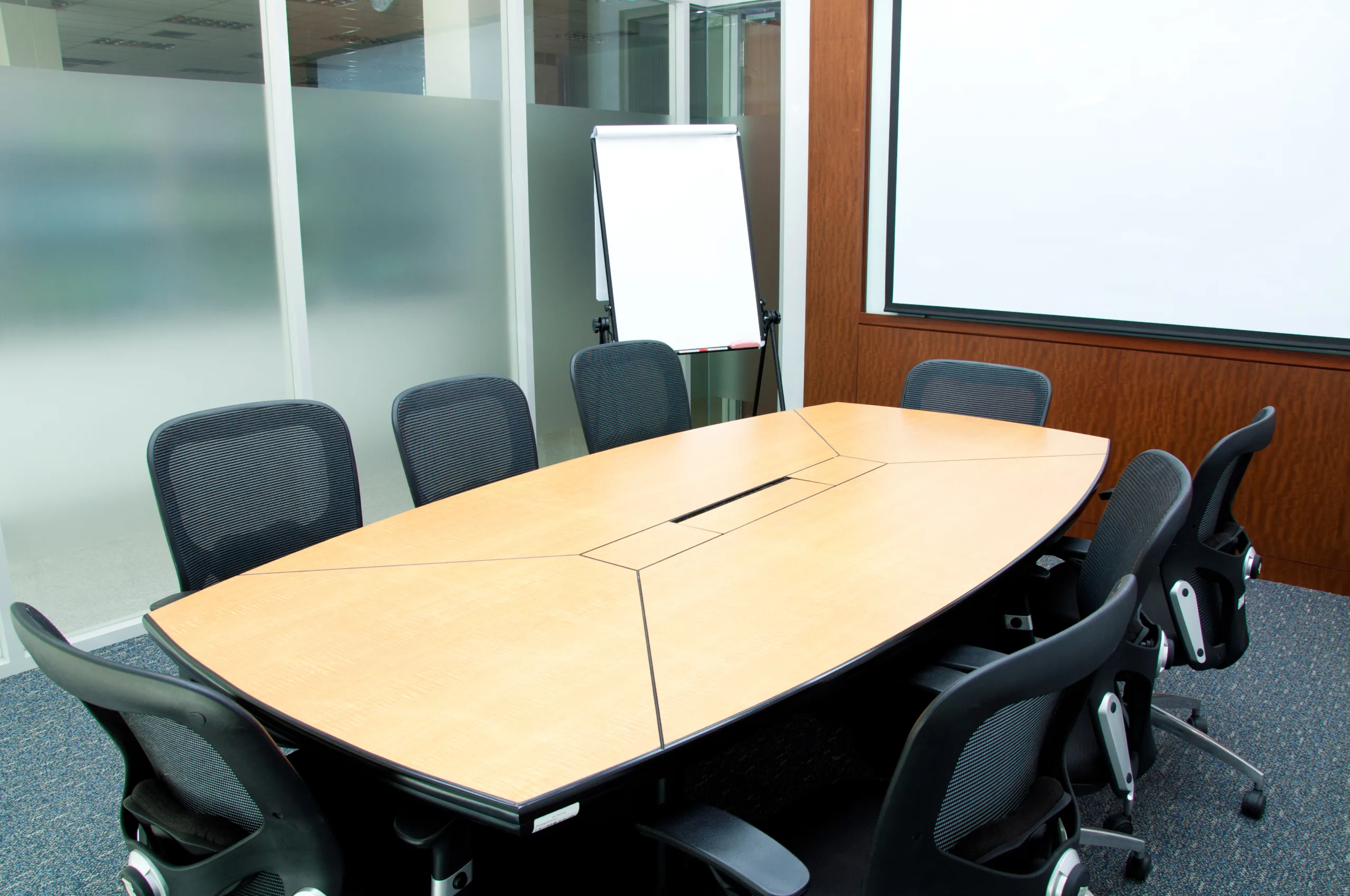 Small,Meeting,Room,With,Flip,Chart A conference room with a wooden table and chairs.
